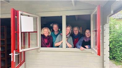 Frauen in Holzhaus gucken aus Fenster