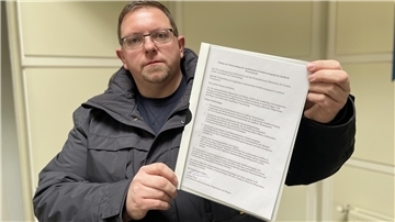 Mann in einer Winterjacke mit einer Petition in der Hand.