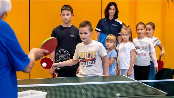 Kinder spielen Tischtennis. 