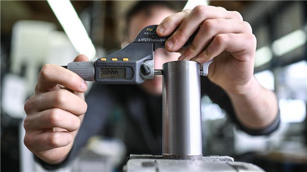 Ein Auszubildender im Metall-Handwerk misst die Dicke eines Werkstücks. 