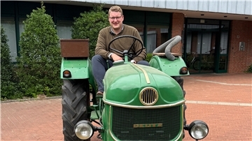 Bürgermeister Henrik Wärner sitzt auf einem Oldtimer-Trecker vor dem Rathaus Schiffdorf.