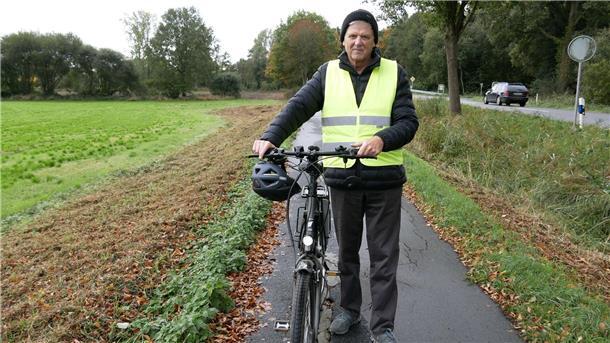 Gefahrenstelle am Radweg Richtung Wilstedt sorgt für Ärger Ein Mann mit einer signalgelben Weste hält ein Fahrrad fest.