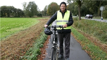 Gefahrenstelle am Radweg Richtung Wilstedt sorgt für Ärger Ein Mann mit einer signalgelben Weste hält ein Fahrrad fest.