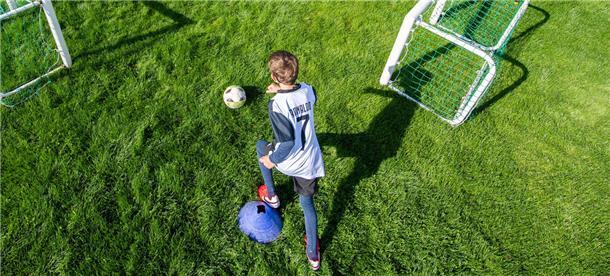 Ein Junge spielt auf dem Rasen Fußball.