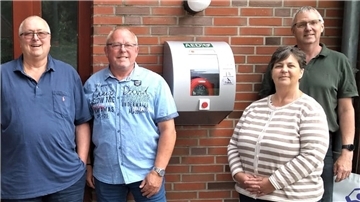 Wolfgang Grube, Ortsbürgermeister Thomas Frese, die 1. Vorsitzende des Vereins "Wehden erleben", Anja Rittmeyer, und der stellvertretende Ortsbürgermeister Christian Schumacher am neuen Defibrillator in Wehden