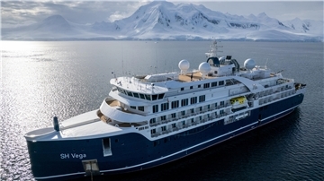 Expeditionskreuzfahrtschiff "SH Vega" auf See vor eisbedeckten Bergen.