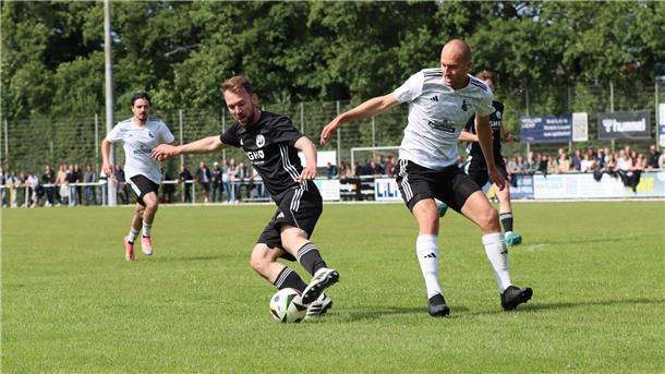 Zwei Männer in Sporttrikots kämpfen um einen Ball.