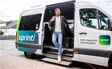 Ein Mann steigt aus einem Kleinbus mit der Aufschrift "sprinti"