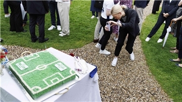 Eine junge Frau fotografiert bei einer Feier eine Torte in Form eines Fußballfeldes.