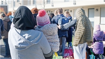 Geflüchtete aus der Ukraine stehen vor den Gebäuden einer Flüchtlingsunterkunft in Köln.