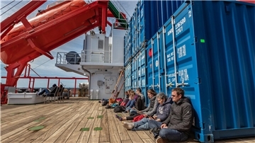 Genießen während der Wartezeit die Sonne: Expeditionsleiter Professor Markus Rex (vorne rechts) und weitere Wissenschaftler auf der „Maria S. Merian“.