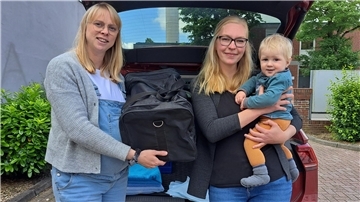 Die jungen Mütter Annika Semmler (links) und Kathrin Schweer zeigen eine gepackte Tasche, saubere Handtücher und Hygieneauflagen, die man für die lange Fahrt in die Geburtsklinik parat haben sollte.