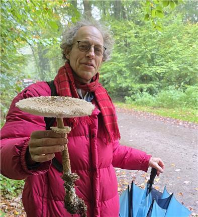 Ein Mann hält einen großen Pilz in die Höhe.