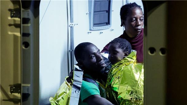 Viele Migranten kommen nach Europa - Wie geht es weiter? Gerettete Migranten gehen auf der italienischen Insel Lampedusa von einem Boot an Land.