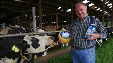 Gerhard Dehlwes im Kuhstall mit selbst produziertem Käse und eigener Biomilch.