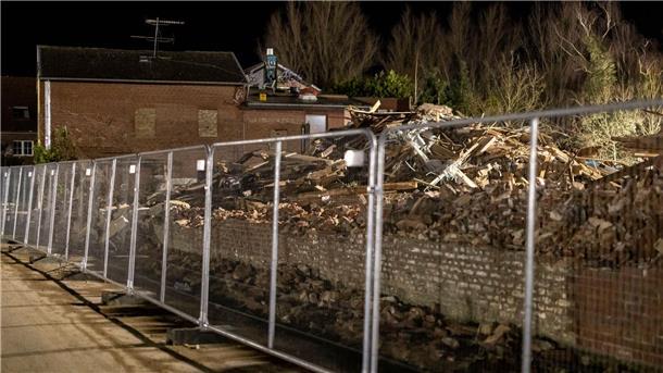 Verbliebene Aktivisten verlassen Tunnel unter Lützerath Gerodete Bäume liegen vor einer Scheune in Lützerath, davor ein Bauzaun zur Absperrung.