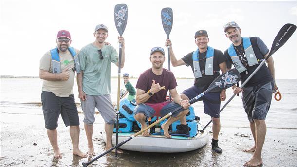 Fünf Männer und ein Stand-up-Paddleboard.