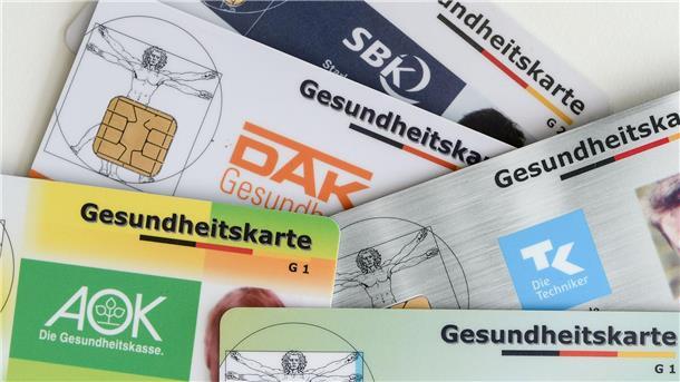 Gesundheitskarten verschiedener Krankenkassen liegen auf einem Tisch. 