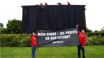 Greenpeace-Aktivisten mit einem Banner vor dem verhüllten Haus des britischen Premiers Rishi Sunak.