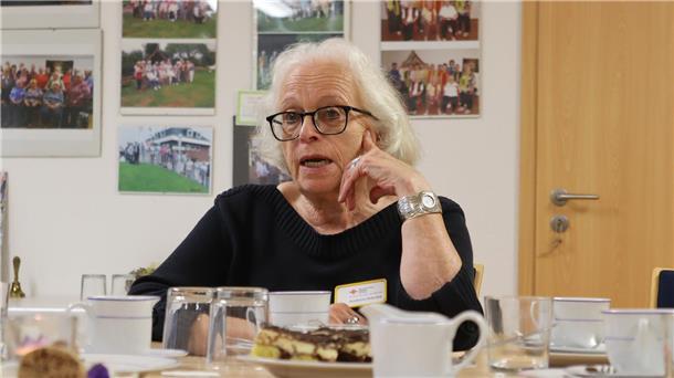 Frau mit schwarzem Pullover an Kaffeetafel