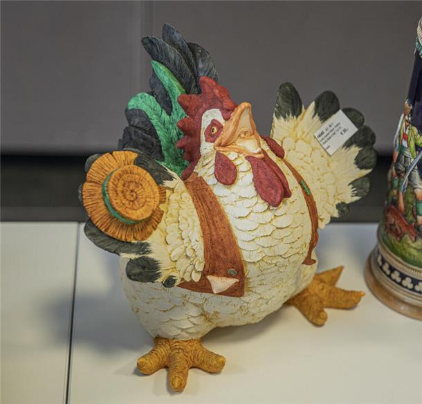 Porzellan-Henne mit Hut und breitem Grinsen.