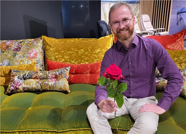 „Ladys Night“ mit einem Hauch Dieter Bohlen im Wohncenter in Nordenham Ein Mann sitzt mit einer roten Rose auf einem bunten Sofa, Hendrik Lenz vom Wohncenter in Nordenham