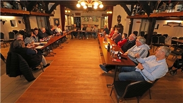 Männer und Frauen sitzen an einem großen Tisch zusammen