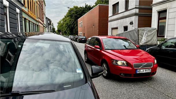 Leerer Parkplatz, volle Straßen: Park-Frust am Stadthaus Bremerhaven Man sieht ein rotes Auto in einer kleinen Straße. Am Rand parken überall Autos.