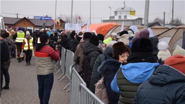 Hoffnung trotz des Leids: Eine geflüchtete Ukrainerin steht mit Hunderten anderen in einer Schlange und wartet darauf, einen der Shuttlebusse zu besteigen, die sie in die Sammelzentren im Umland bringen.