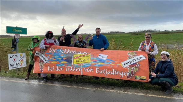 Männer und Frauen in Karnevalskostümen hinter einem Banner
