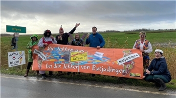 Männer und Frauen in Karnevalskostümen hinter einem Banner