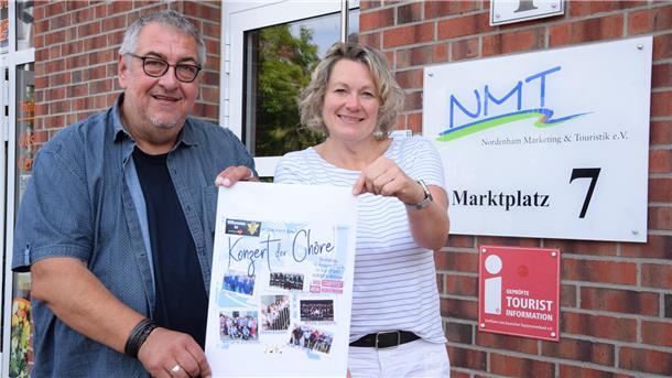 Beim Stadtfest in Nordenham wird viel gesungen: Diese Chöre treten auf Ein Mann und eine Frau halten ein Plakat des Konzerts der Chöre in den Händen.