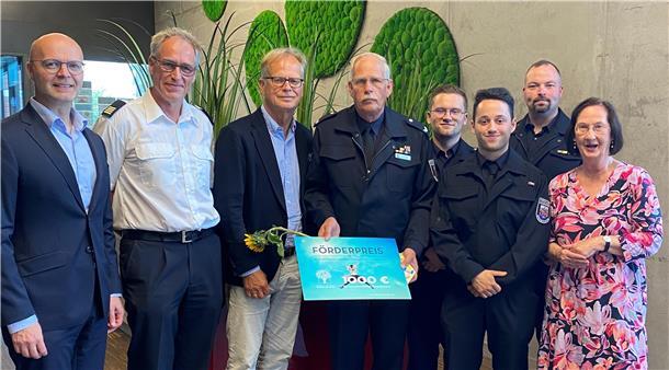 Gruppenfoto bei der Verleihung des Dr. Henning Hübner Förderpreises: Acht Personen stehen nebeneinander, darunter Preisträger Malte Hoheisel in Uniform mit Urkunde und Sonnenblume, umgeben von Mitgliedern der Feuerwehr und der Bürgerstiftung Bremerhaven.