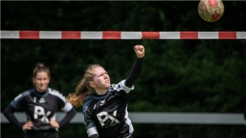 Eine Frau schlägt einen Ball über ein rotweißes Band.