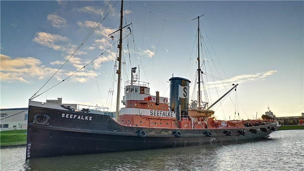 Der historische Bergungsschlepper „Seefalke“ liegt im Museumshafen des Deutschen Schifffahrtsmuseums in Bremerhaven, umgeben von ruhigem Wasser und Abendlicht.