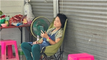 Im Schatten und mit Ventilator: Eine Frau in Bangkok versucht, sich sich abzukühlen.