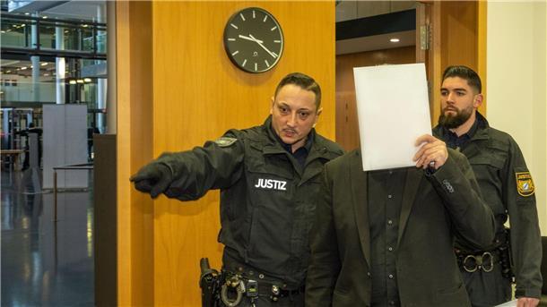 Ermordung von Tochter geplant - Vater und Bruder vor Gericht Im Strafjustizzentrum bringen zwei Justizwachtmeister einen Mann in den Sitzungssaal. Er ist zusammen mit seinem Sohn am Amtsgericht Augsburg angeklagt.