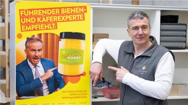 Honig-Streit mit Böhmermann geht in nächste Instanz Imker Rico Heinzig neben einem Plakat mit dem Foto des Moderators Jan Böhmermann.