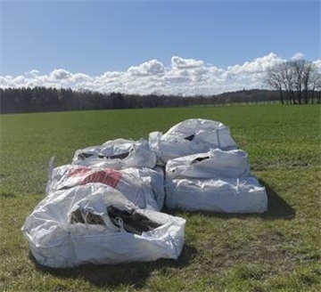 Sechs weiße Big-Bags liegen auf einer grüner Wiese. Es handelt sich um einen Fall illegaler Müllentsorgung. 