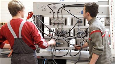 Zwei junge Männer stehen an einer hydraulischen Anlage