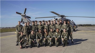 Eine Gruppe von 23 Jugendlichen in olivgrüner Uniform steht auf einem Flugplatz vor einem Marinehubschrauber des Typs NH90. Es ist sonnig, der Himmel ist blau. 
