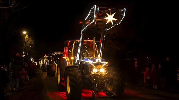 Aktion „Ein Funken Hoffnung“ zurück: Traktor-Konvois durch Wesermarsch geplant Beleuchtete Traktoren fahren auf einer Straße, links und rechts stehen Zuschauer.