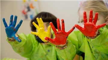 Zwei Kinder haben ihre Finger bemalt und halten ihre Hände in die Kamera.