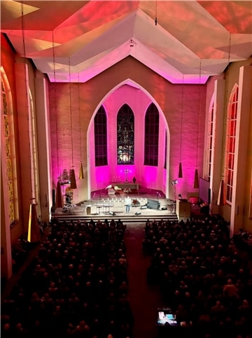 eine Kirche, vor dem Altar sitzen viele Leute