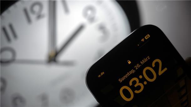 Ein Smartphone zeigt die Uhrzeit «03:03» an, während auf einer analogen Uhr noch 02:03 Uhr ist. Am 26. März werden die Uhren um 02:00 Uhr auf 03:00 Uhr vorgestellt und die Sommerzeit beginnt.
