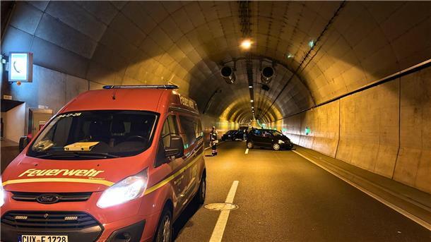Blick in eine Tunnelröhre. Im Vordergrund ein Feuerwehrwagen, im Hintergrund mehrere Pkw. Sie stehen quer zur Fahrbahn.