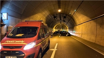 Blick in eine Tunnelröhre. Im Vordergrund ein Feuerwehrwagen, im Hintergrund mehrere Pkw. Sie stehen quer zur Fahrbahn.