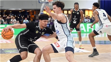 Ein Basketballer ist auf dem Weg zum Korb, ein Gegenspieler stellt sich ihm in den Weg.