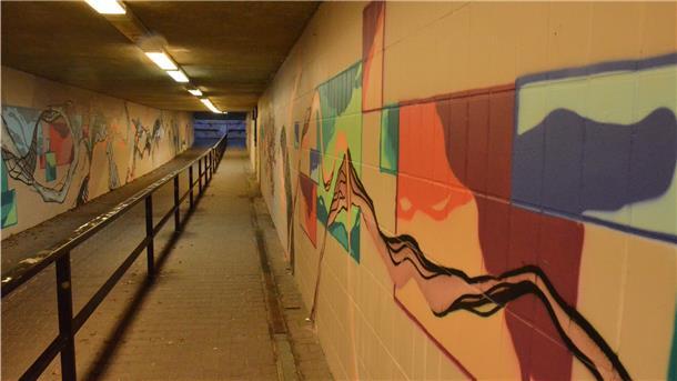Ein Tunnel mit mehreren Graffiti an den Wänden.