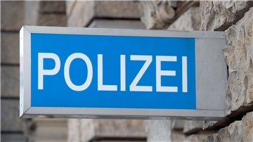 Ein Polizeischild hängt an einer Häuserfassade.